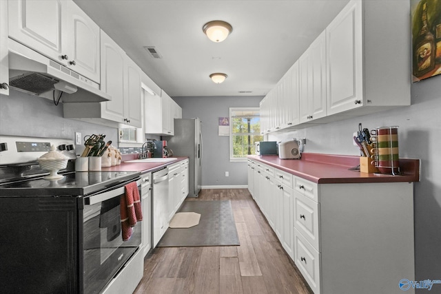 kitchen featuring appliances with stainless steel finishes, white cabinetry, wood-type flooring, and sink