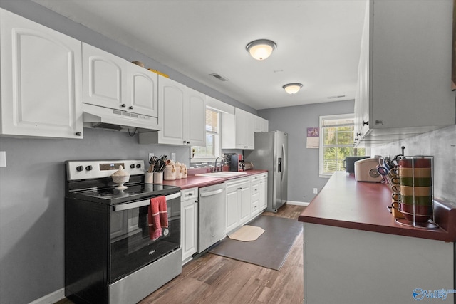 kitchen featuring wood-type flooring, sink, appliances with stainless steel finishes, and white cabinets