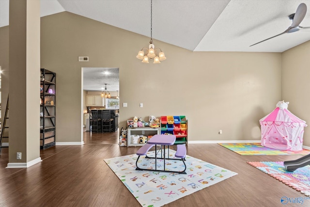 rec room featuring dark wood-type flooring, a textured ceiling, vaulted ceiling, and ceiling fan with notable chandelier