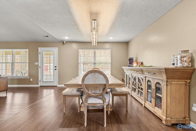 dining space featuring a textured ceiling, a healthy amount of sunlight, and dark hardwood / wood-style flooring