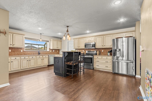 kitchen featuring cream cabinets, a kitchen island, hanging light fixtures, a kitchen breakfast bar, and stainless steel appliances