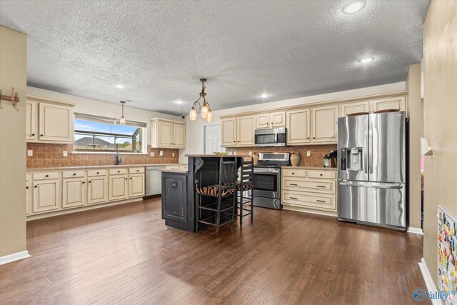 102 Bay Pointe Ln, Madison, AL 35758 - kitchen featuring cream cabinetry, appliances with stainless steel finishes, a textured ceiling, a breakfast bar area, and light countertops
