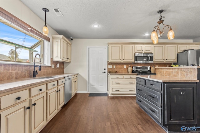 kitchen featuring dark wood-type flooring, appliances with stainless steel finishes, decorative light fixtures, and sink