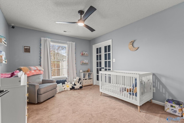 bedroom featuring ceiling fan, a textured ceiling, carpet floors, and a nursery area