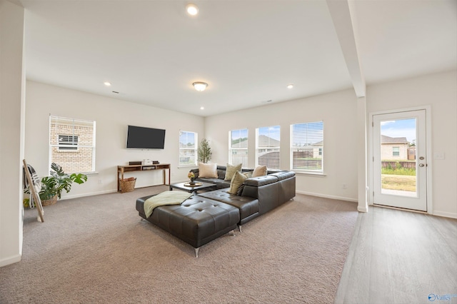 living room featuring plenty of natural light, beamed ceiling, and light hardwood / wood-style floors