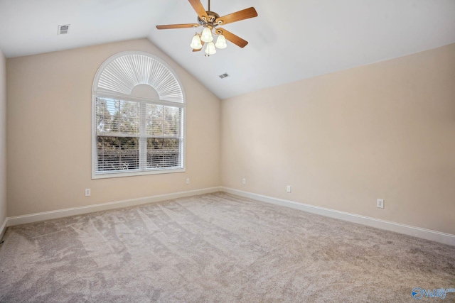 carpeted spare room featuring vaulted ceiling and ceiling fan