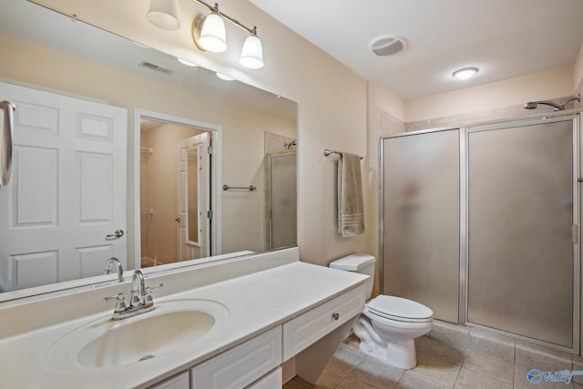 bathroom featuring a shower with door, vanity, tile patterned floors, and toilet