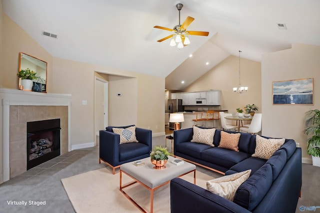 living room featuring a tile fireplace, ceiling fan with notable chandelier, light carpet, and high vaulted ceiling