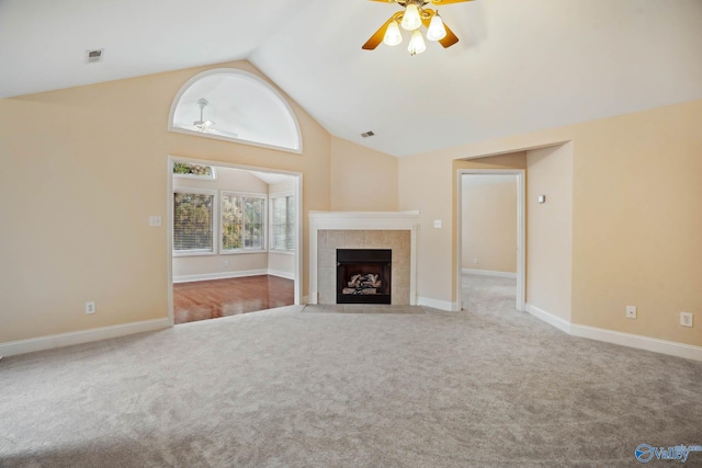 unfurnished living room with a tiled fireplace, high vaulted ceiling, light colored carpet, and ceiling fan