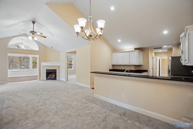 kitchen featuring lofted ceiling, hanging light fixtures, stainless steel fridge, light colored carpet, and white cabinets