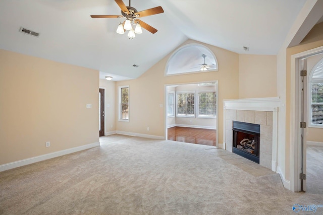 unfurnished living room with ceiling fan, high vaulted ceiling, light carpet, and a tile fireplace