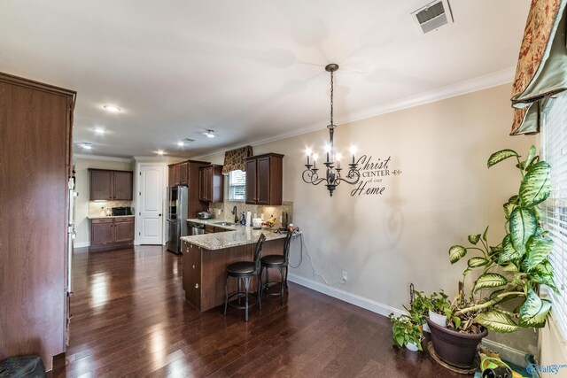 1117 Pegasus Dr NW, Huntsville, AL 35806 - kitchen with appliances with stainless steel finishes, a kitchen breakfast bar, a chandelier, backsplash, and a peninsula
