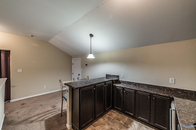 1117 Pegasus Dr NW, Huntsville, AL 35806 - kitchen featuring vaulted ceiling, a peninsula, hanging light fixtures, dark cabinetry, and a breakfast bar area