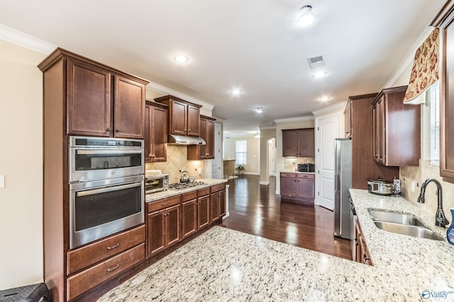 1117 Pegasus Dr NW, Huntsville, AL 35806 - kitchen featuring stainless steel appliances, ornamental molding, under cabinet range hood, light stone countertops, and backsplash