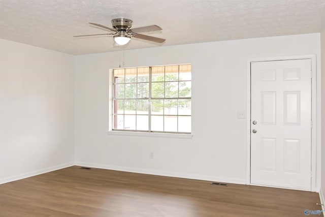 empty room with visible vents, a ceiling fan, a textured ceiling, wood finished floors, and baseboards