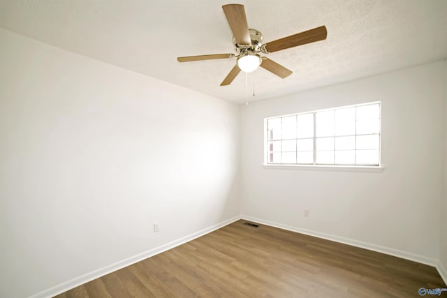 spare room with visible vents, ceiling fan, baseboards, wood finished floors, and a textured ceiling