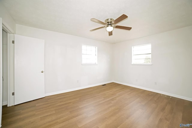 unfurnished room with wood finished floors, baseboards, plenty of natural light, and ceiling fan