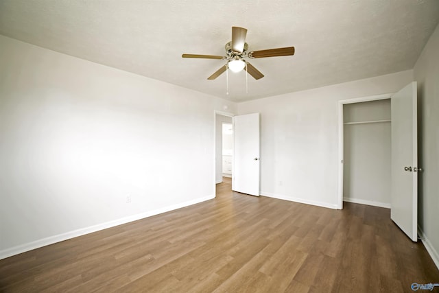 unfurnished bedroom featuring a ceiling fan, wood finished floors, baseboards, a closet, and a textured ceiling