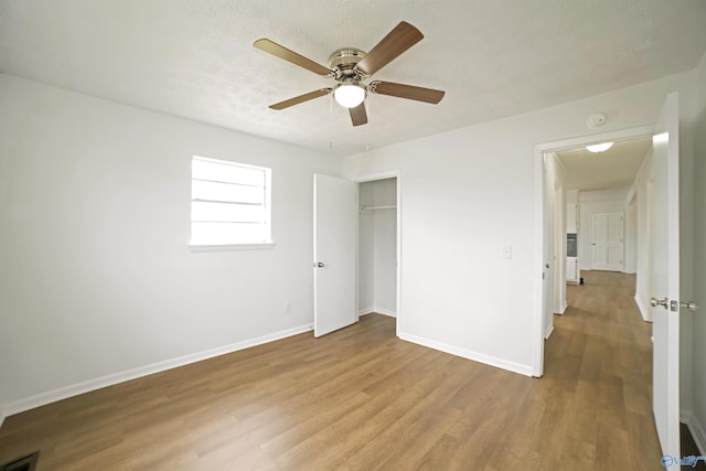 unfurnished bedroom with visible vents, a textured ceiling, wood finished floors, a closet, and baseboards