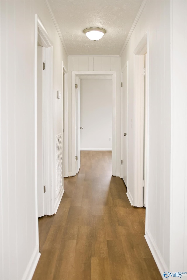 hallway featuring ornamental molding, a textured ceiling, and wood finished floors