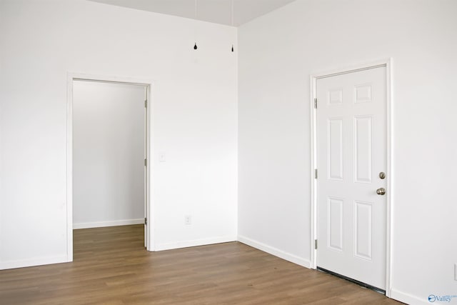 spare room with baseboards and wood finished floors