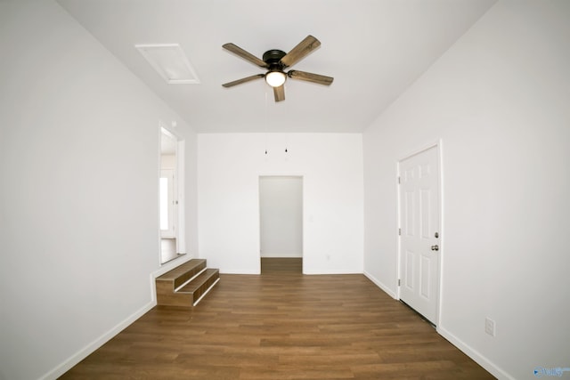 empty room with baseboards, attic access, wood finished floors, and a ceiling fan