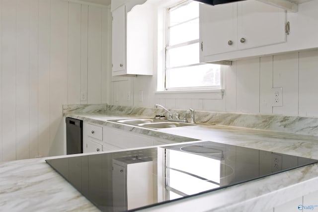 kitchen featuring a sink, light countertops, dishwasher, wood walls, and white cabinetry