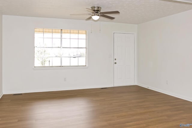 empty room with visible vents, a ceiling fan, a textured ceiling, wood finished floors, and baseboards