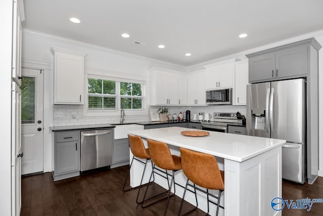 kitchen with sink, a breakfast bar area, appliances with stainless steel finishes, a center island, and ornamental molding