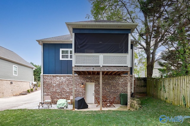 rear view of house featuring a patio, a sunroom, and a lawn