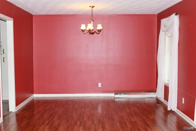 spare room featuring an inviting chandelier, a textured ceiling, baseboards, and wood finished floors