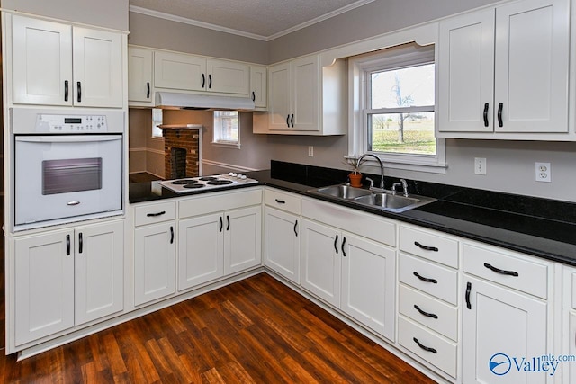 7853 Danville Rd, Danville, AL 35619 - kitchen featuring white appliances, dark countertops, a sink, dark wood-style floors, and crown molding