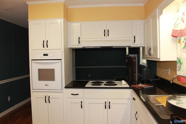 kitchen featuring ornamental molding, white appliances, and a sink