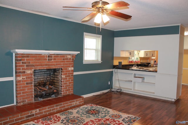 living area with a fireplace, dark wood finished floors, ornamental molding, a ceiling fan, and baseboards