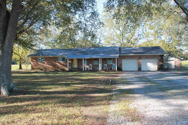 ranch-style home with a porch, an attached garage, brick siding, a front lawn, and gravel driveway