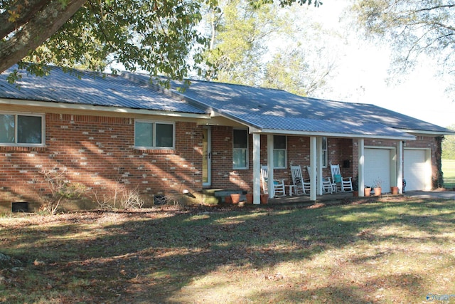 ranch-style home featuring a garage, covered porch, metal roof, and brick siding