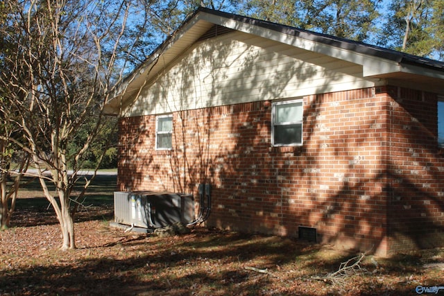 view of side of property with brick siding, crawl space, and cooling unit