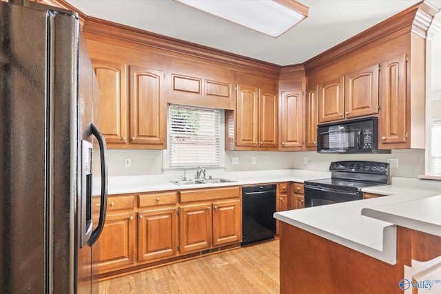 kitchen featuring black appliances, light wood-type flooring, and sink