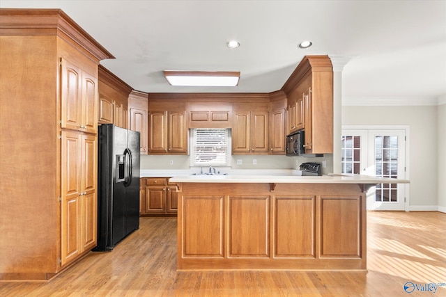 kitchen featuring kitchen peninsula, ornamental molding, sink, black appliances, and light hardwood / wood-style flooring