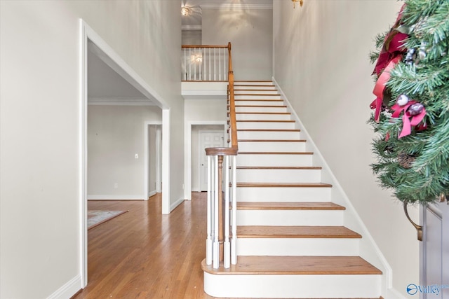 stairway featuring wood-type flooring and crown molding