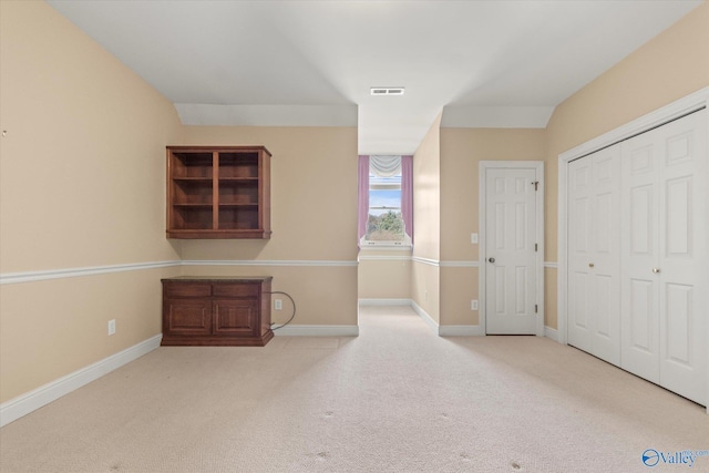 unfurnished bedroom featuring a closet and light colored carpet