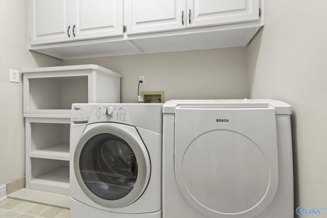 clothes washing area with cabinets and washing machine and dryer