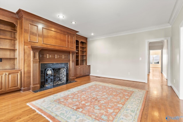 living room with light hardwood / wood-style floors, crown molding, and a premium fireplace