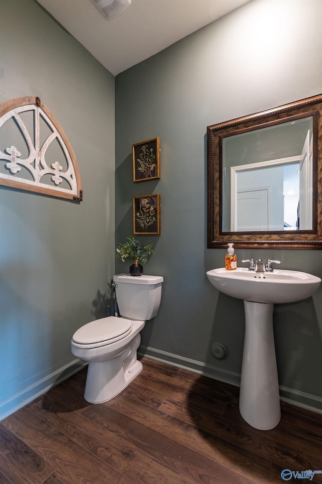 bathroom featuring visible vents, baseboards, a sink, toilet, and wood finished floors