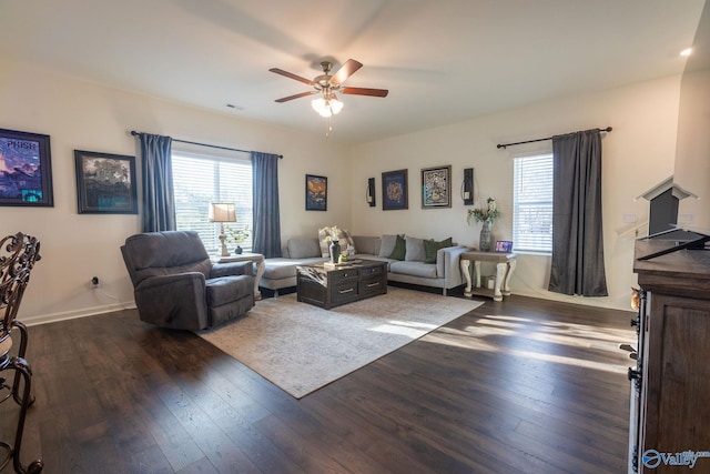 living area featuring dark wood finished floors, ceiling fan, visible vents, and a healthy amount of sunlight