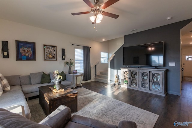 living room featuring a ceiling fan, visible vents, stairway, wood finished floors, and baseboards