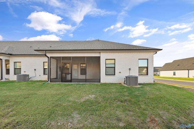 rear view of property with a sunroom, a lawn, and central AC unit