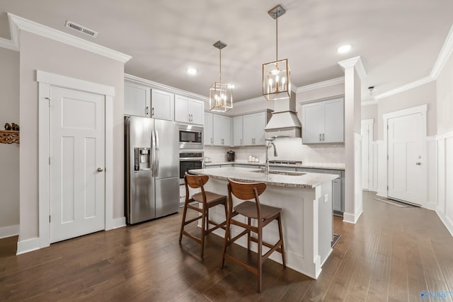 kitchen featuring light stone countertops, dark wood-type flooring, appliances with stainless steel finishes, and an island with sink