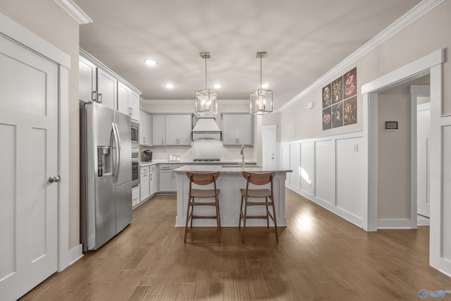 kitchen featuring dark hardwood / wood-style flooring, appliances with stainless steel finishes, an island with sink, a kitchen bar, and sink