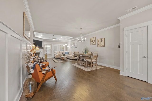 dining room featuring ornamental molding, dark hardwood / wood-style floors, a tray ceiling, and ceiling fan with notable chandelier